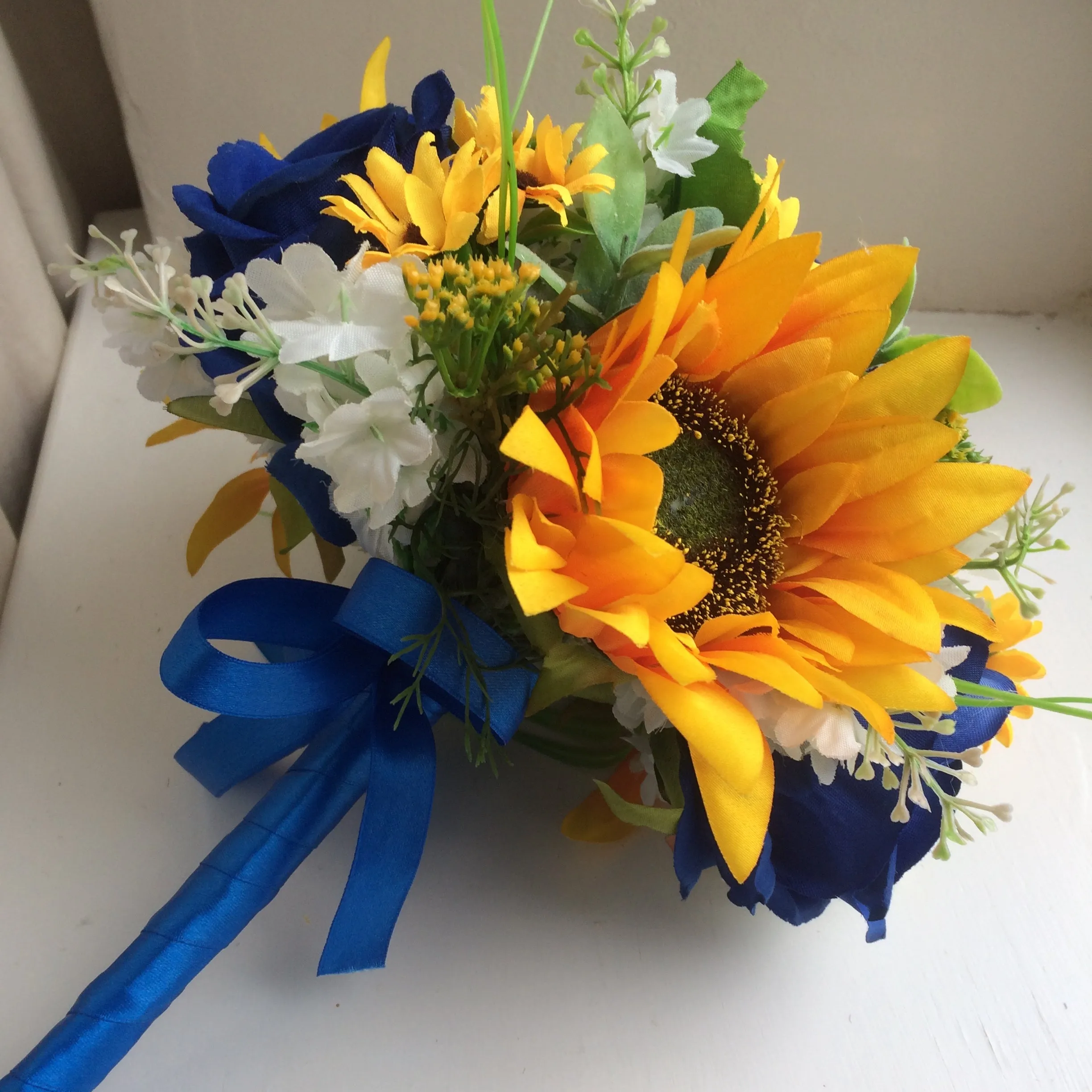 A collection of wedding bouquets featuring  sunflowers and either royal or navy blue roses